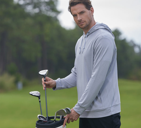 Model wearing MAELREG Classic Heather Golf Hoodie takes a club from bag, calm and focused.