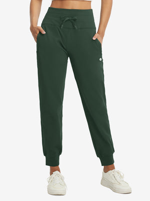 Model wearing women's stretch fleece lined water resistant joggers in forest green, showcasing the front lower body view.