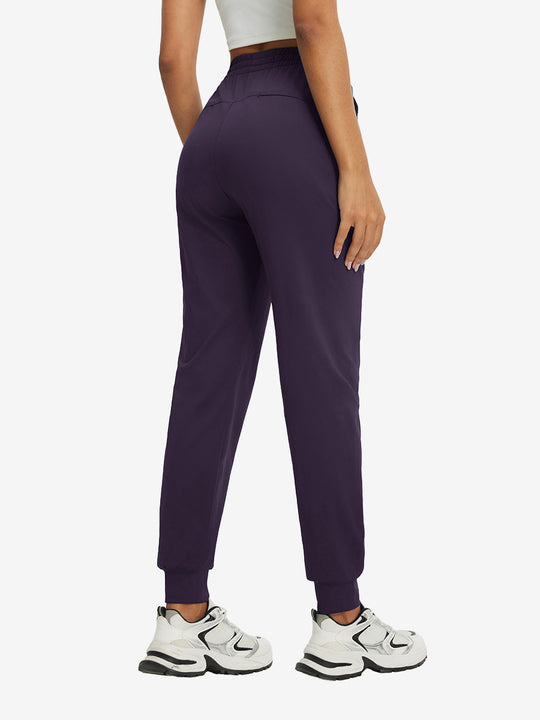 Back view of lightweight women's stretchy joggers sweatpants on model, shown in dark purple.