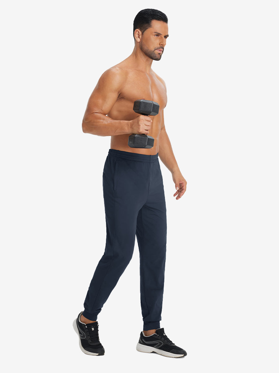 Model holding tennis racket wearing lightweight traning track pants in navy.