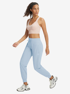 Full-body front view of model wearing women's stretch fleece lined water resistant joggers in light grayish blue.