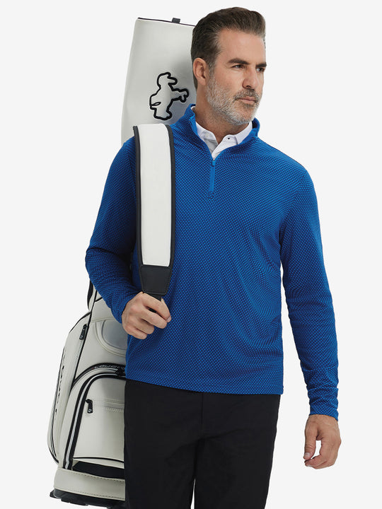 Model carrying a golf bag in jacquard quarter zip pullover in cobalt, blending comfort and style.