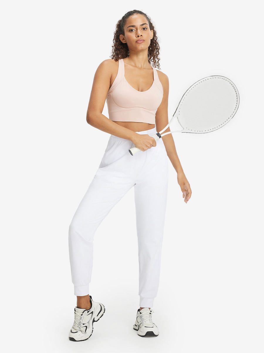 Model holding golf club behind neck while wearing lightweight women's stretchy joggers sweatpants in white.