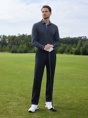 Model in dark grey long sleeve solid jersey polo holding a golf club outdoors, full-body shot