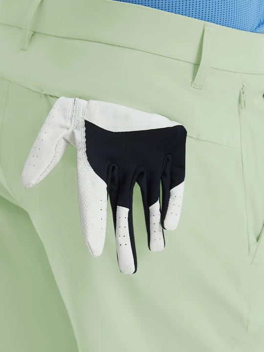 Back view of Player Fit Versatile Solid Shorts 7 Inch with golf glove tucked into right pocket – LIGHT GREEN