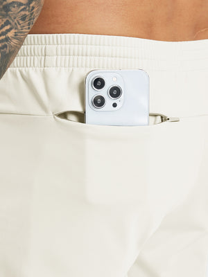 Back pocket detail of Water Resistant Comfy Fleece Golf Joggers in cream, holding smartphone
