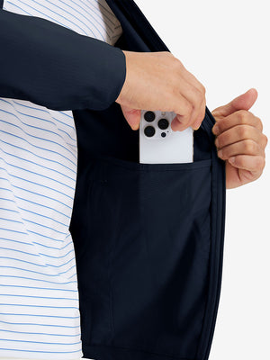 Hand placing iPhone into inner pocket of lightweight water-resistant outerwear jacket in navy