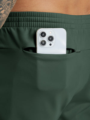 Back pocket detail of Water Resistant Comfy Fleece Golf Joggers in forest green, holding smartphone