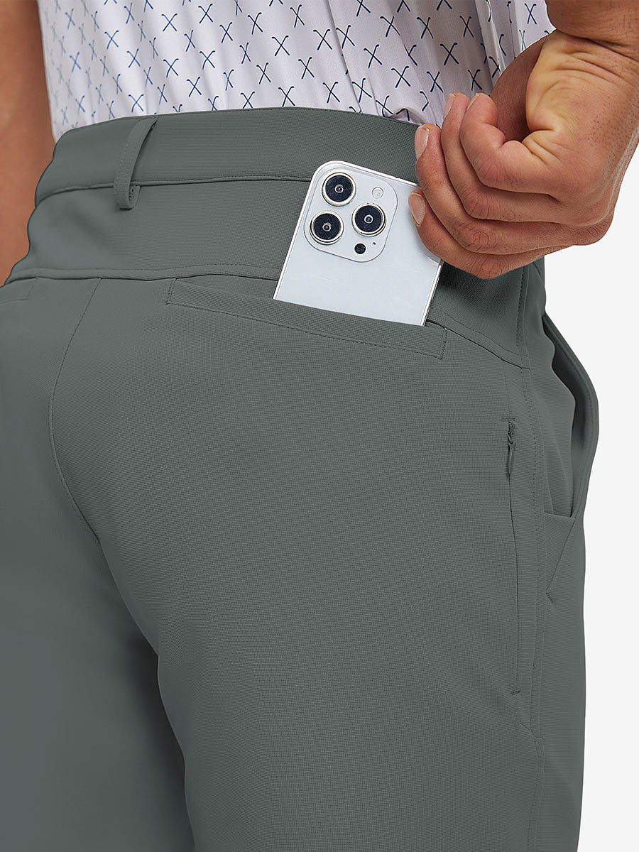 Back view of model putting phone into pocket while wearing lightweight moisture wicking dress pants in slate green.