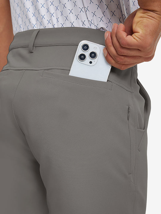 Back view of model putting phone into pocket while wearing lightweight moisture wicking dress pants in dark khaki.