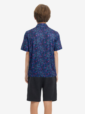 Back half-body view of youth wearing navy colorful flower performance print boys golf polo, showing rear design